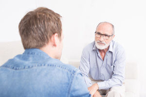 A counselor meets with a man to discuss inpatient vs outpatient