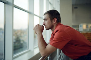 man looks out window at drug addiction treatment center