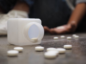 hand holds white tablets while others spill on the floor from a bottle and show the need for a xanax addiction treatment center